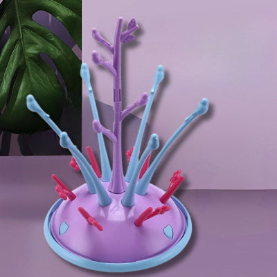 Sèche biberon violet et bleu en forme d’arbre fleuri, idéal pour organiser les accessoires de bébé dans un petit espace.


