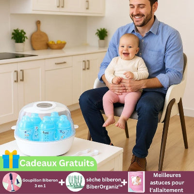 Papa souriant avec son bébé dans une cuisine moderne, devant un stérilisateur biberon micro-ondes rempli de biberons bleus. Cadeaux gratuits : goupillon biberon 3-en-1, sèche-biberon BiberOrganiz™ et guide allaitement.