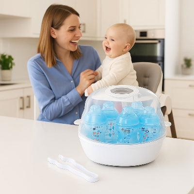 Maman souriante avec son bébé dans une cuisine blanche, à côté d’un stérilisateur biberon micro-ondes rempli de biberons bleus. Solution rapide et hygiénique pour jeunes parents.

