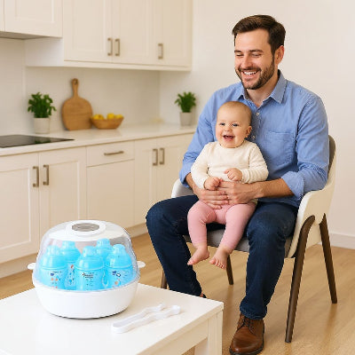 Papa heureux tenant son bébé sur les genoux, devant un stérilisateur biberon micro-ondes sur une table. Gain de temps et hygiène express pour le quotidien.

