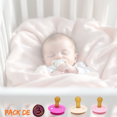Nourrisson dormant paisiblement dans son lit avec une sucette pour nourrisson blanche, accompagnée d’un pack de 3 tétines coloris rose, beige et pastel pour un usage quotidien.