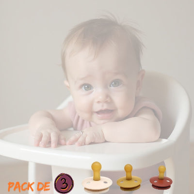 Bébé assis sur une chaise haute avec présentation du pack DouceSuccion™ comprenant 3 tétines caoutchouc biberon naturelles sans BPA et une attache tétine sécurisée.