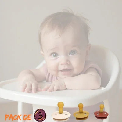 Bébé assis sur une chaise haute avec présentation du pack DouceSuccion™ comprenant 3 tétines caoutchouc biberon naturelles sans BPA et une attache tétine sécurisée.
