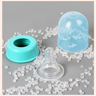 Vue rapprochée d’une tétine en silicone, capuchon et bague turquoise posés sur des granules de silicone alimentaire – composants de biberon sûrs et sans BPA.