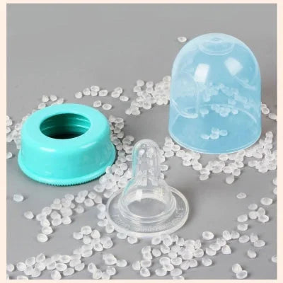 Vue rapprochée d’une tétine en silicone, capuchon et bague turquoise posés sur des granules de silicone alimentaire – composants de biberon sûrs et sans BPA.