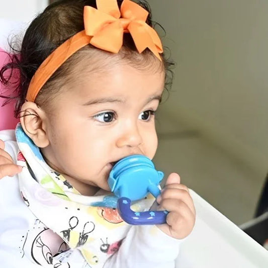 Bébé utilisant une tétine grignoteuse bleue pour découvrir les fruits en toute sécurité