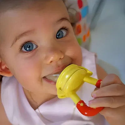 Bébé souriant utilisant une tétine grignoteuse jaune pour manger des fruits