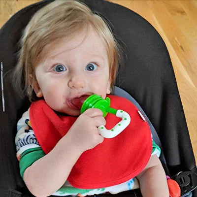 Bébé tenant une tétine grignoteuse verte et apprenant à manger seul