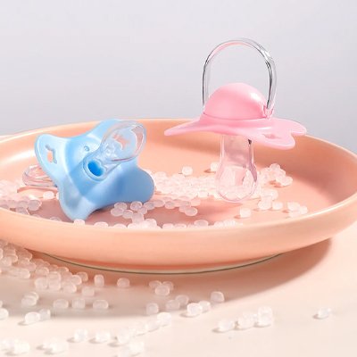 Tétines en silicone alimentaire rose et bleue sur une assiette, design doux et hygiénique