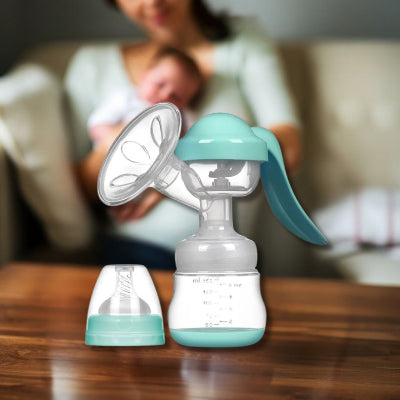Tire-lait manuel bleu avec coussin en silicone doux, posé sur une table avec une maman et son bébé en arrière-plan.